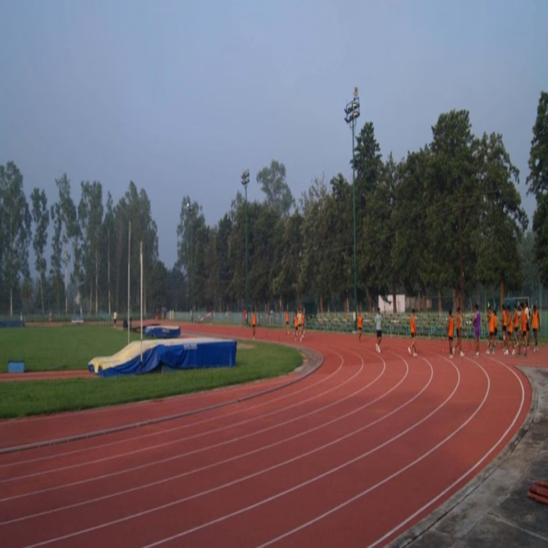 Track athletes running at full speed on a rubberized track with stadium in background